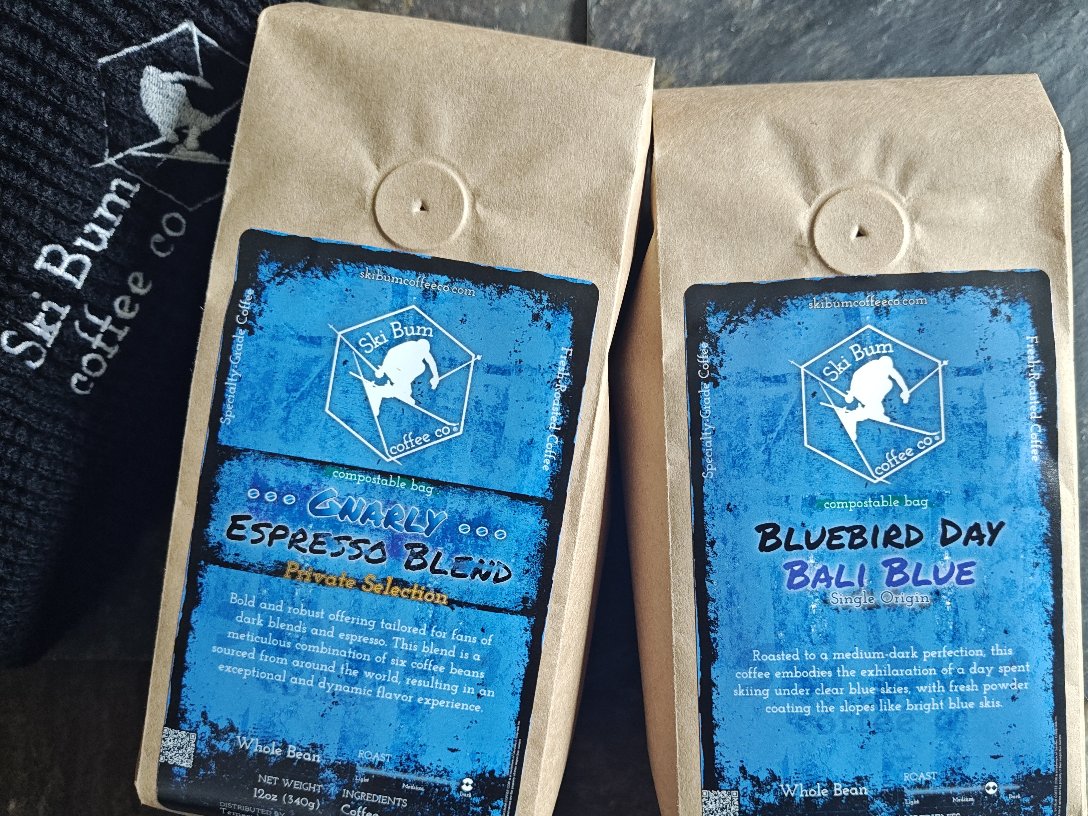 Two coffee bags (Gnarly Espresso Blend, and Bluebird Day Bali Blue) on a stone surface
