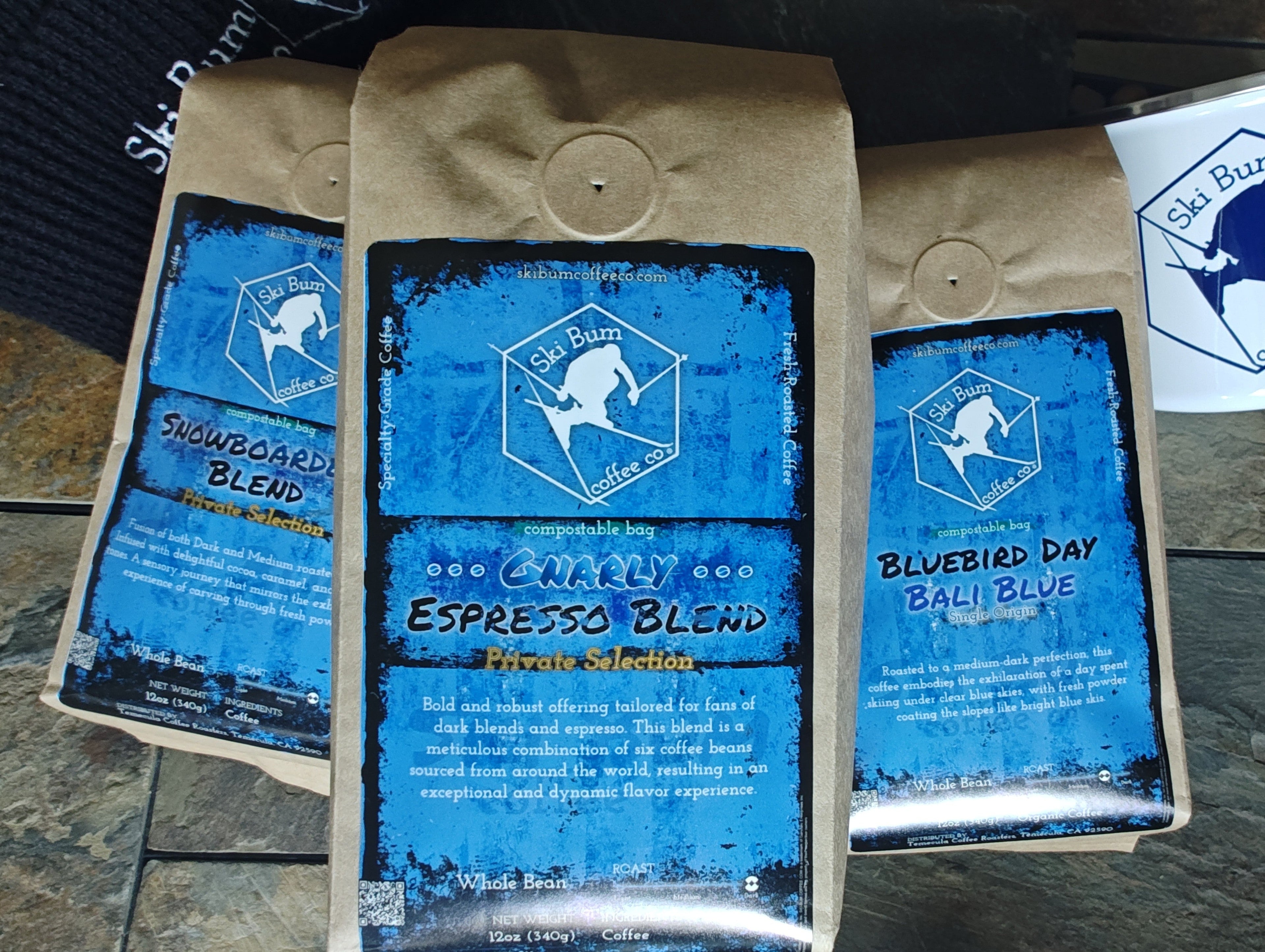 Three coffee bags from Ski Bum Coffee Co. on a stone surface.