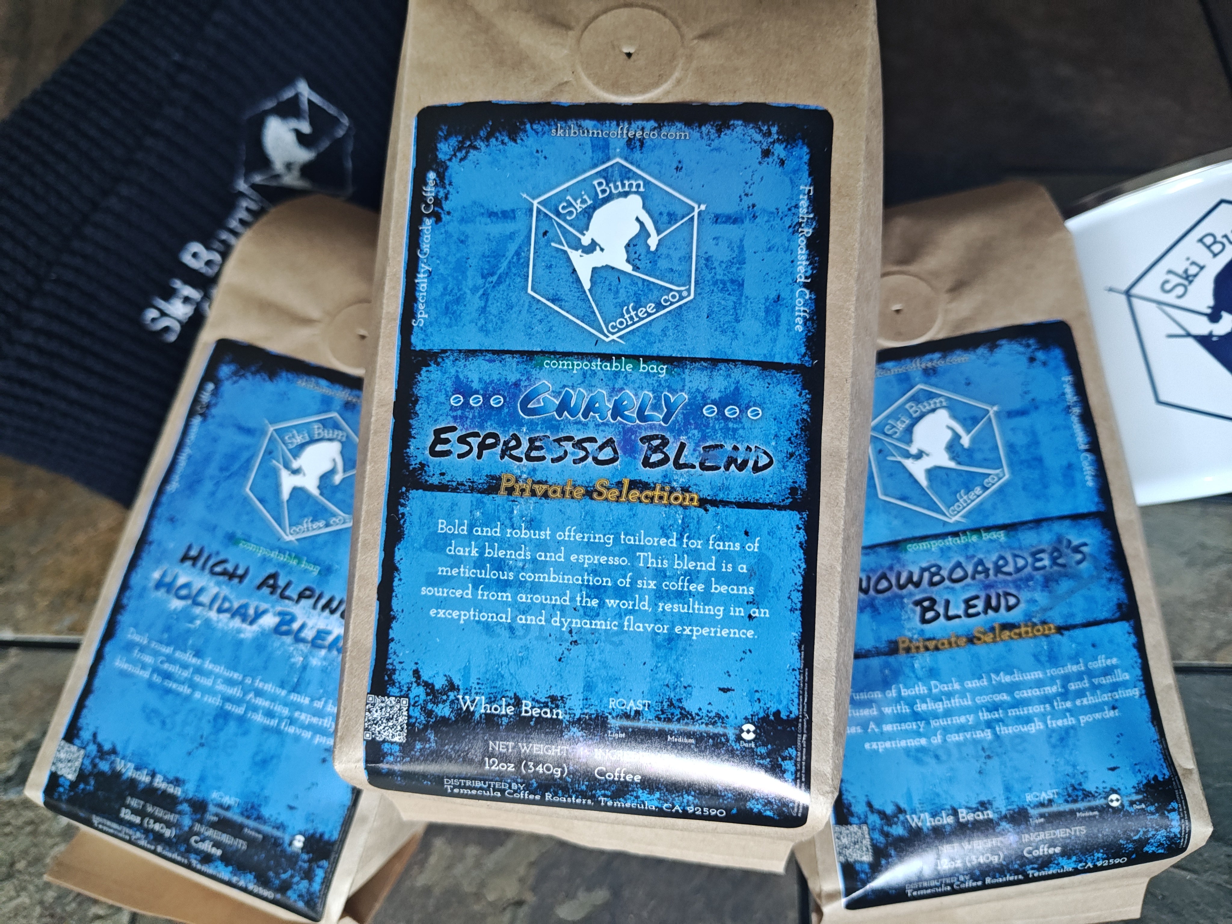 Three coffee packages from Ski Bum Coffee Co on a stone surface.